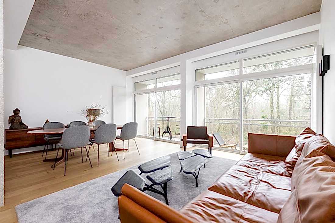 Salon avec sofa en cuir marron et plafond en béton