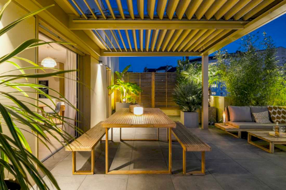 Terrasse bioclimatique avec pergola - espace repas avec vue vers l'intérieur - vue nocturne